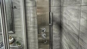 Un baño moderno con cabina de ducha de vidrio, inodoro a la vista y lavabo con espejo.