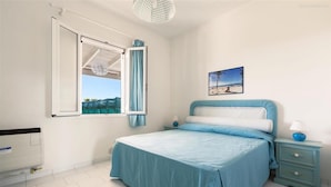 Ein Schlafzimmer mit Bett, Nachttisch, Fenster und einem Bild an der Wand.