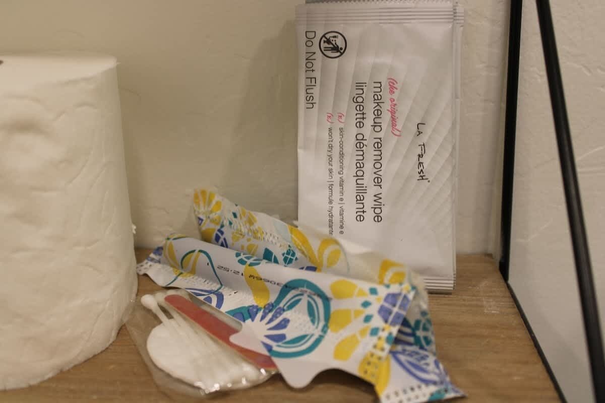 A bathroom with a toilet paper roll, a package of makeup remover wipes, and a tissue box.
