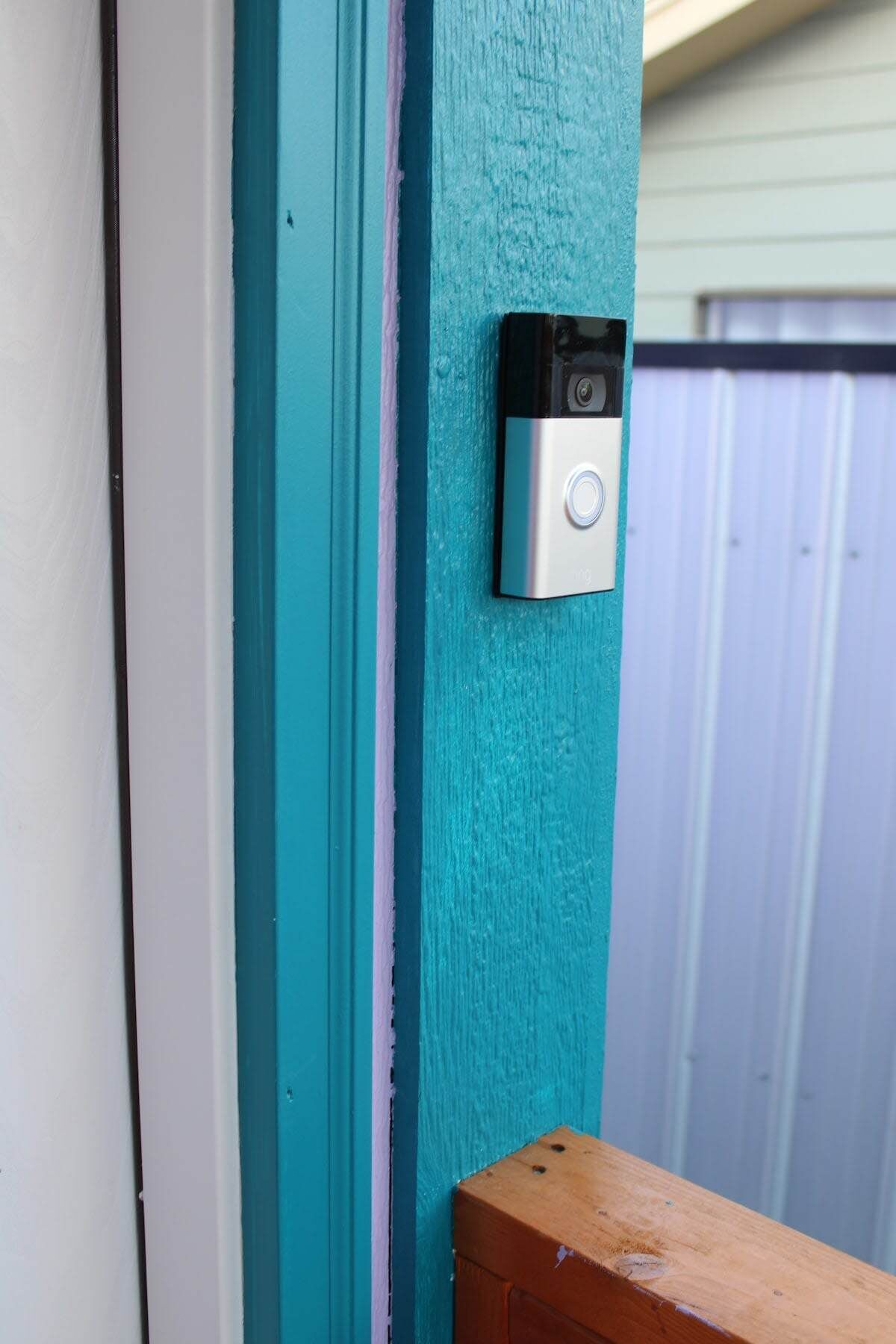 Une porte de couleur bleu-vert avec une caméra de surveillance fixée dessus.