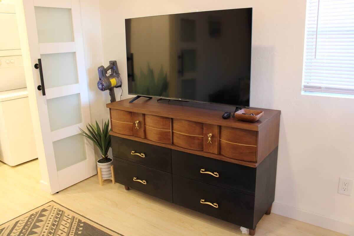 A room with a wooden cabinet, a flat-screen TV, a potted plant, and a door with frosted glass panels.