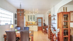 A dining area with a wooden table and chairs, a chandelier, and a kitchen in the background. - 2 bedroom amazing home in Orihuela (Orihuela)