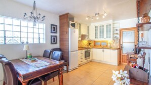 A kitchen with white cabinets, a microwave, and a sink. There is a dining table with chairs and a chandelier. - 2 bedroom amazing home in Orihuela (Orihuela)