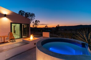 Un área de piscina moderna al aire libre con una chimenea, asientos y vistas del paisaje.