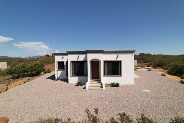 Una casa moderna con camino de grava, ventanas grandes y puerta de madera.