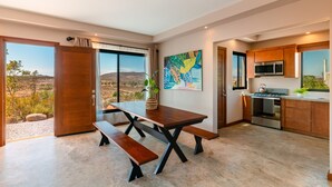 A modern kitchen with a large island, a dining area with benches, and a view of the desert landscape.
