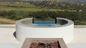 A circular hot tub with a clear view of a mountainous landscape in the background.