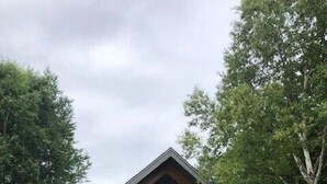 A log cabin with a large front porch and a covered entryway.