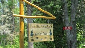 A wooden sign with the text "THE BRINKMAN'S At the Cove 2008" in a forested area.