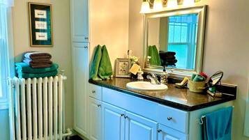 A bathroom with a white radiator, a sink with a mirror above it, and a blue patterned rug on the floor.