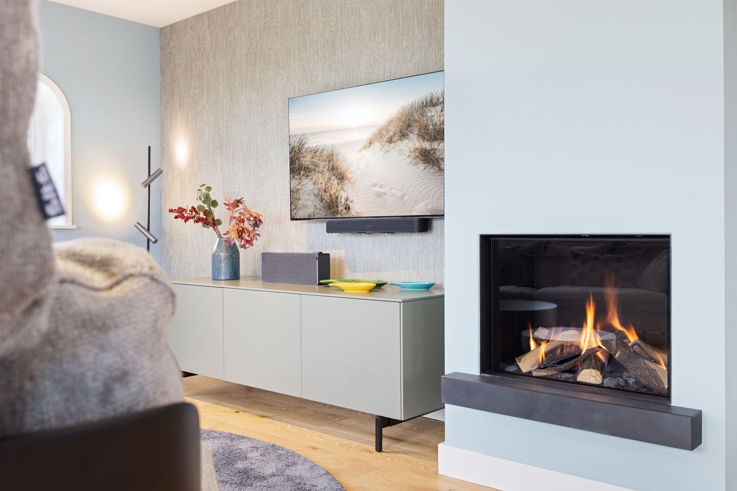 A modern living room with a fireplace, a mounted TV, and a minimalist console table.