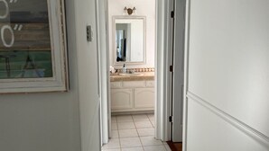 A hallway leading to a bathroom with a tiled floor, a sink, and a mirror. - Freshly remodeled, wonderfully located home in North Sarasota. (Sarasota)