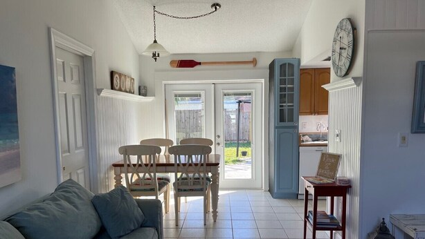 A cozy living room with a sofa, dining table, chairs, and a kitchen area visible through an open door. - Freshly remodeled, wonderfully located home in North Sarasota. (Sarasota)