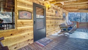 A wooden cabin with a porch, a door with a welcome mat, and a sign that reads "Great Outdoors." - Private - Spacious- Creek Lined Cabin  (Cosby)