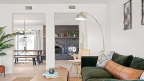 A living room with a green sofa, a coffee table, a fireplace, and a dining area with a table and chairs.