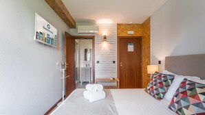 Et hotelværelse med en seng, en bænk, et badeværelse med et spejl og et skilt på væggen.