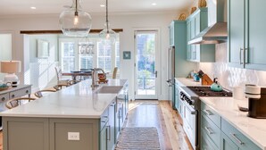 A modern kitchen with a large island, wooden flooring, and light blue cabinets.