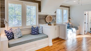 A cozy kitchen with built-in seating, wooden flooring, and large windows with blinds.