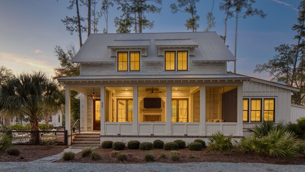 A two-story house with a porch, large windows, and a well-maintained lawn.