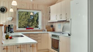 A modern kitchen with wooden cabinetry, a built-in oven, a sink, and a window overlooking a forest. - Stunning home in Rødby with sauna (Rødby)