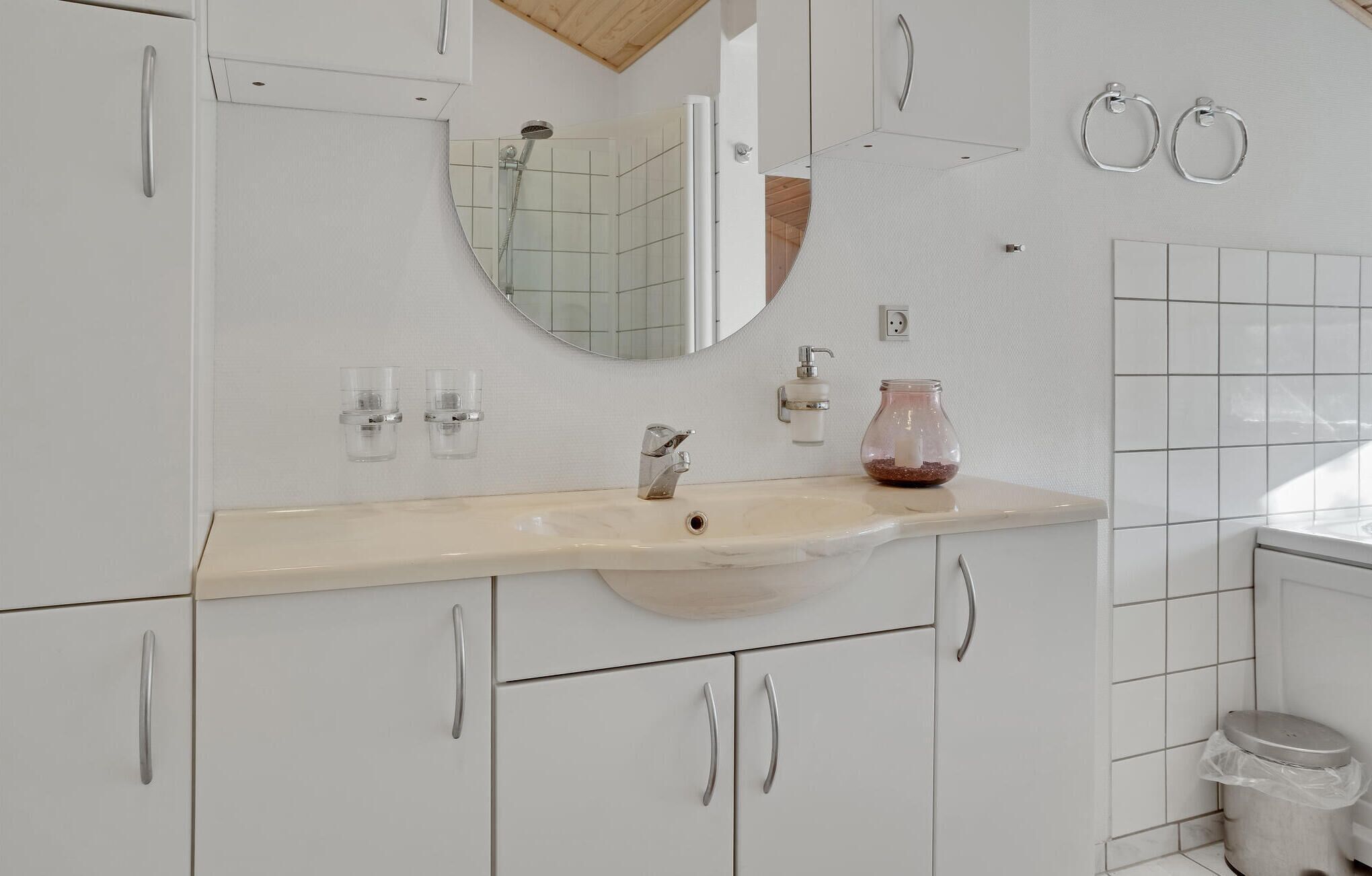 A bathroom with a white sink, a mirror, a shower, and a toilet.