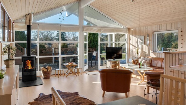 A spacious living area with a fireplace, large windows, and a television. - Stunning home in Rødby with sauna (Rødby)