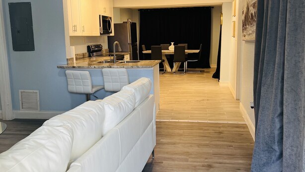 A modern kitchen with white cabinets, a built-in oven, and a dining area with a black table and chairs. - 3bdrm Entertainment Home (orlando)