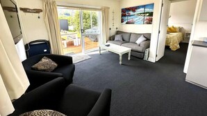 A compact living space with a sofa, a coffee table, and a painting on the wall. - Pohara's Seaside Chalet - Cosy Beach Stay (Pōhara)