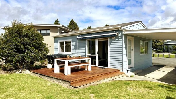A single-story house with a wooden deck and a covered patio area. - Pohara's Seaside Chalet - Cosy Beach Stay (Pōhara)