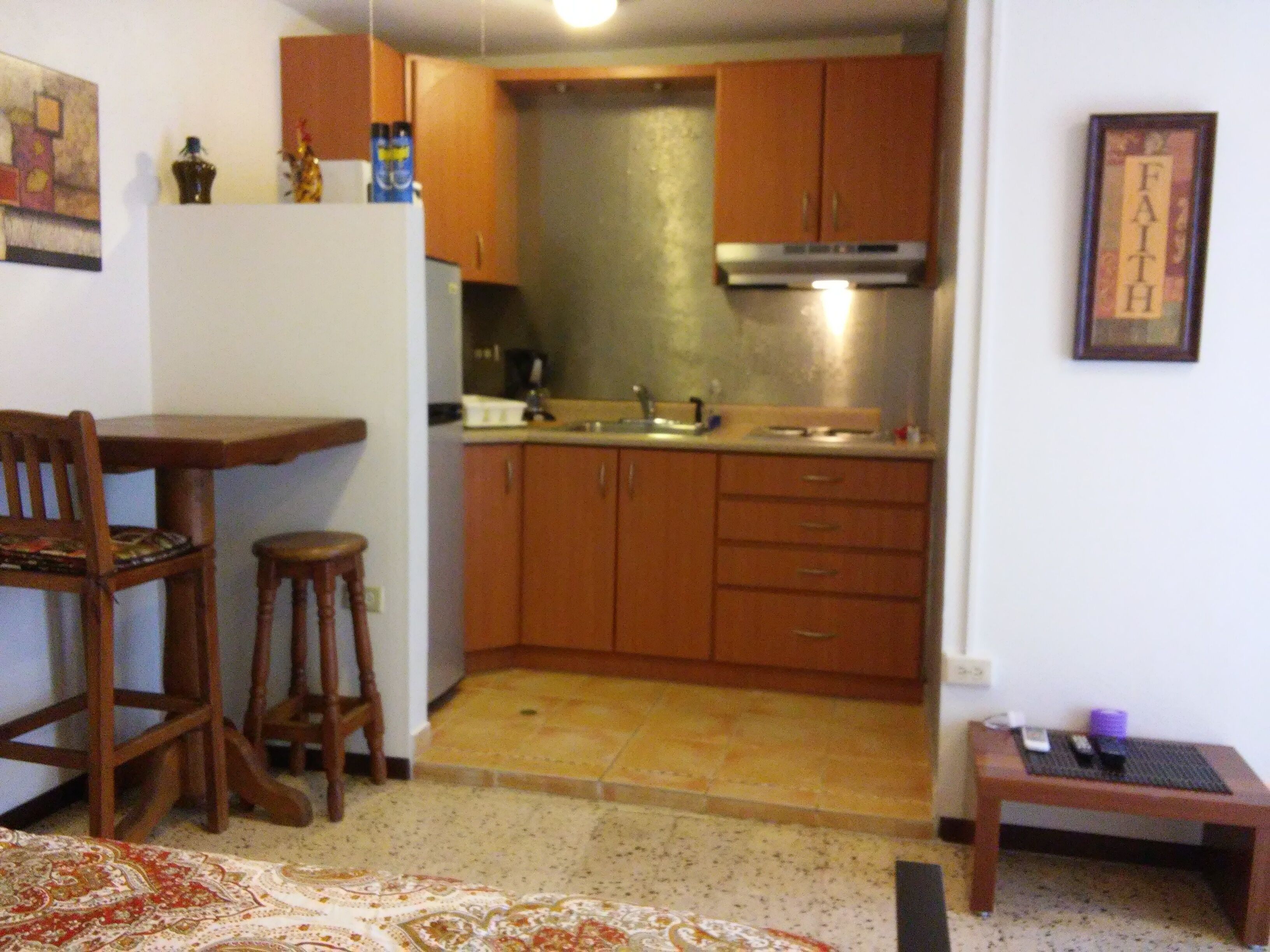 A compact kitchen with wooden cabinets, a countertop, and a sink. There is a dining area with a table and chairs.
