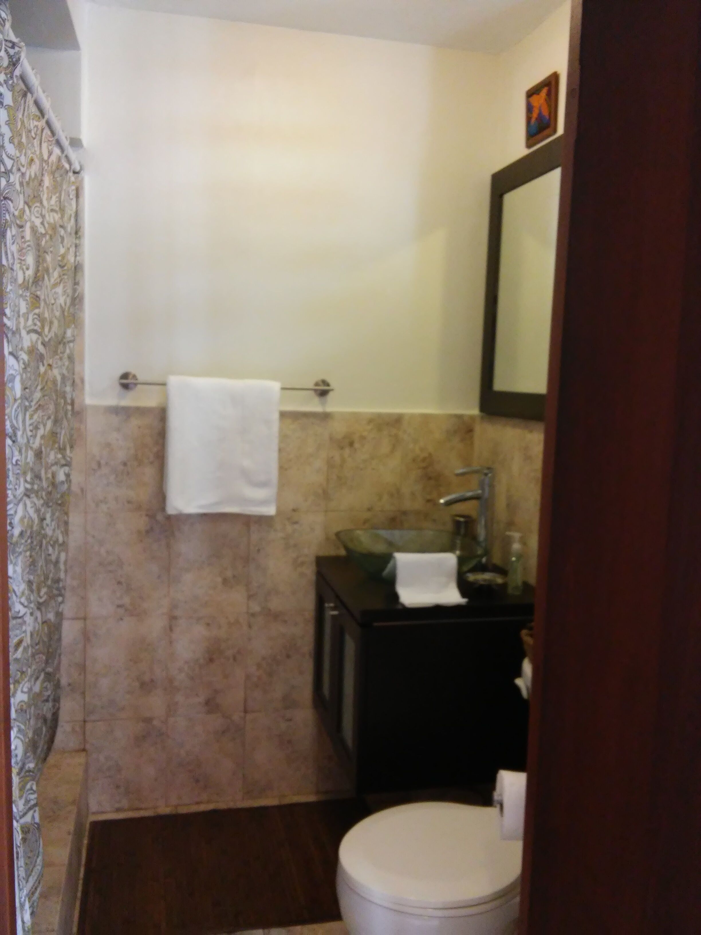 A bathroom with a toilet, sink, and mirror.