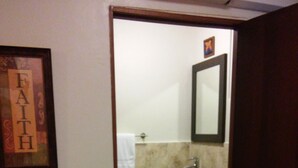 Ein Badezimmer mit Toilette, Waschbecken und Spiegel. Ein gerahmtes Bild hängt an der Wand und es gibt einen Handtuchhalter.