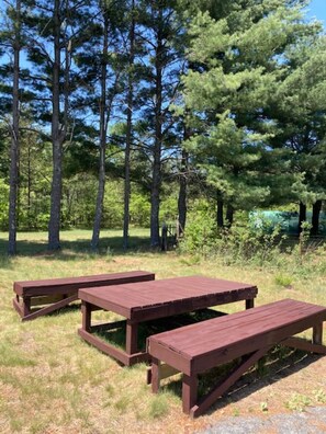 Una mesa de picnic en un área con césped y árboles al fondo.