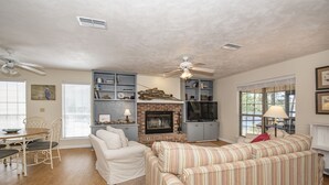 A living room with a fireplace, a sofa, a dining table, and a TV. - Osprey House, Osprey House (Wakulla County)