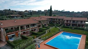 A residential building with a swimming pool, multiple balconies, and a well-maintained garden. - Maison Elisa a Manerba By Bookinggardalake (Manerba del Garda)