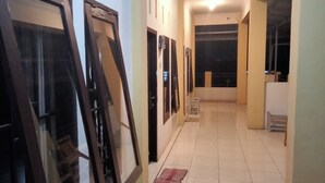 Un pasillo con varias puertas, algunas con paneles de vidrio, que dan a diferentes habitaciones. El suelo está cubierto de baldosas y hay una alfombra pequeña cerca de la entrada.