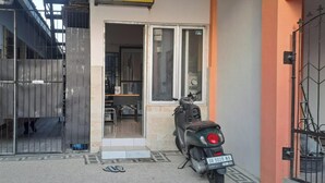 Una entrada con portón a un edificio, con una moto estacionada afuera.
