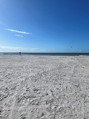 A wide, open beach with a clear sky and a few people walking.