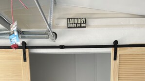 A laundry room with two front-loading washing machines, wooden cabinets, and a sign above reading "Laundry Loads of Fun".