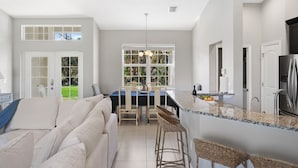 Een moderne keuken met een groot eiland, witte kasten en uitzicht op de omgeving.