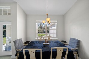 A dining room with a table set for six, a chandelier, and a view of the outdoors through large windows. - PRIVATE, SPACIOUS, COZY & CLEAN!! CLOSE TO EVERYTHING. GULF COAST 20 MIN AWAY 🏝 (North Port)