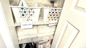Armazém com caixas etiquetadas contendo extintores, kit de primeiros socorros, recipiente com gelo seco, materiais para falta de energia, toalhas extras e roupa de cama suja.
