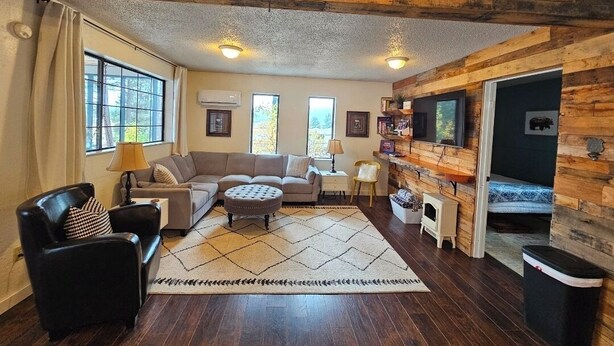 A living room with a sofa set, a coffee table, a fireplace, and a TV mounted on a wooden wall.