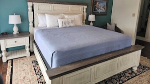 A bedroom with a bed, nightstands, a lamp, a framed picture, and a door.