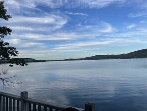 Un lac paisible, avec une jetée en bois et des collines en arrière-plan.