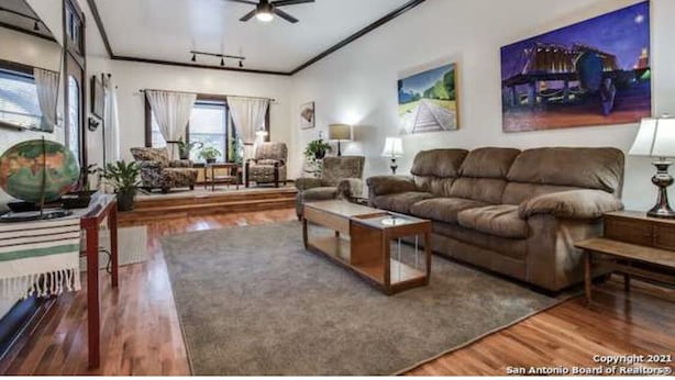 A spacious living room with a brown leather sofa, a wooden coffee table, and a globe on a side table. - Alamo City Former Library Historic Home, Parking, BBQ, Firepit, Gated Side-Yards (San Antonio)