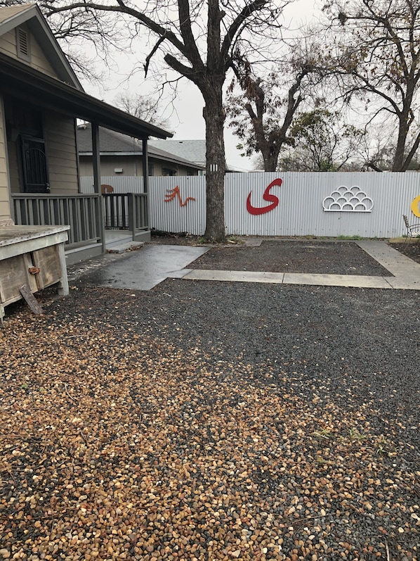 A building with a covered porch, a fenced area with a logo, and a gravel driveway.