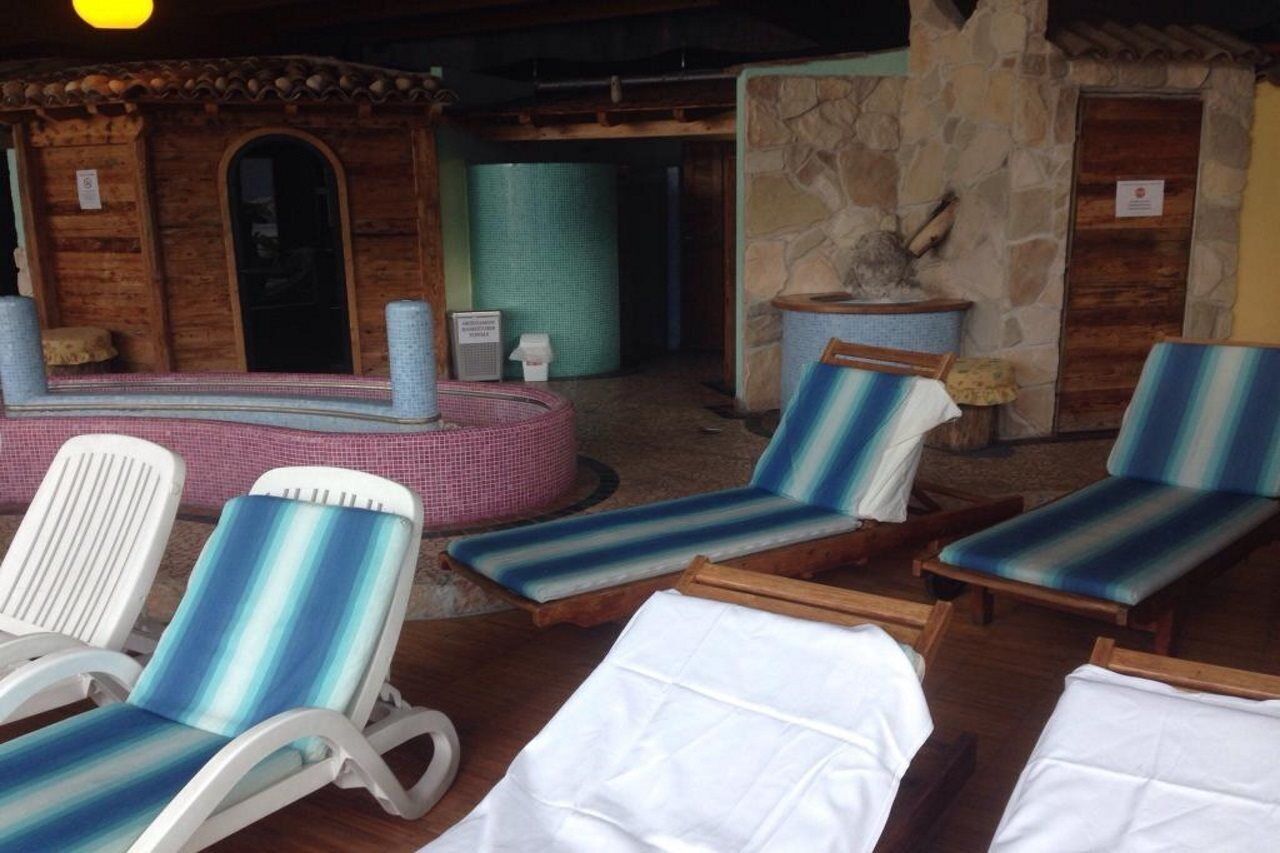 Un área de spa con sillones de descanso, pared de piedra y una pequeña piscina.
