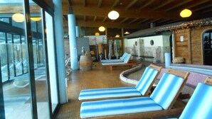 Un área de spa con vigas de madera, ventanas grandes y tumbonas.