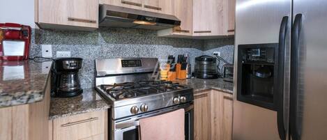 A kitchen with wooden cabinets, a stainless steel stove, a refrigerator, and a coffee maker.